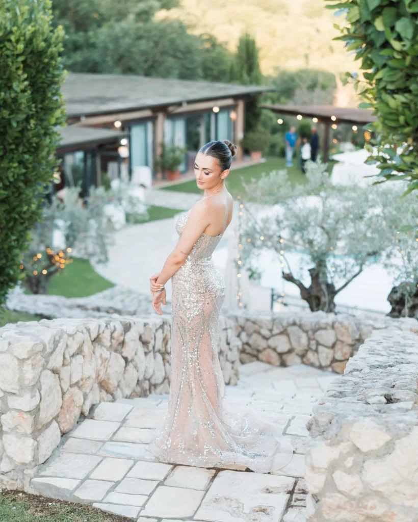 Ragazza alta e bellissima con vestito brillantinato seduta sulle scale durante uno shooting fotografico On Air Eventi, con sfondo di piscina scenografica, scalinata in mattoni e giardino verde a Roma e Latina